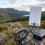 Portable satellite internet device connected to a battery pack on rocks outdoors